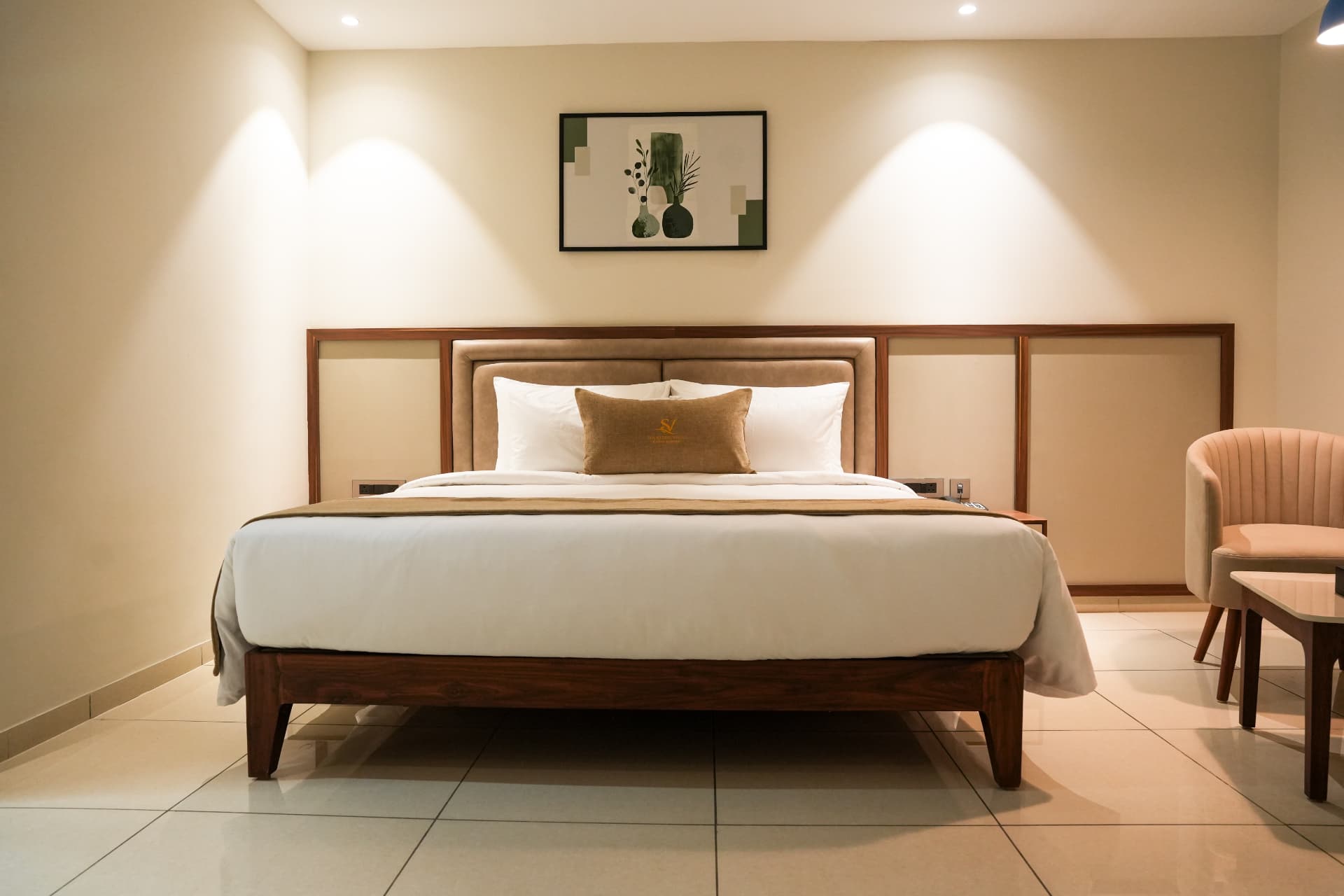 The Club Room bed, made with white linen beneath framed artwork