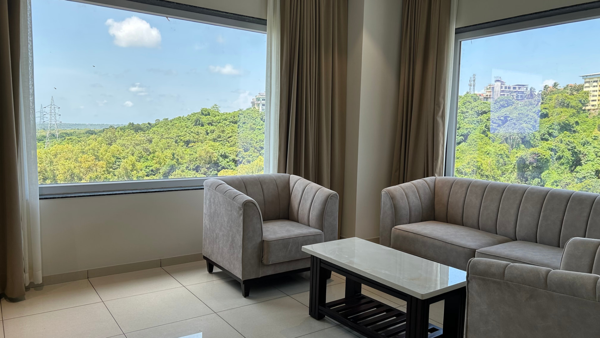 The Suite lounge: sofa and armchairs beside a corner window onto greenery