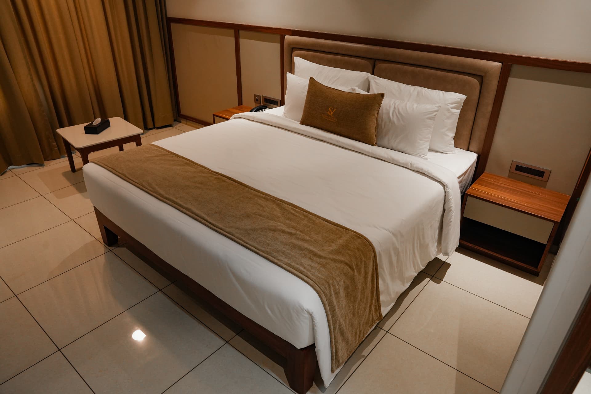 The Premium Room bed, made with white linen and a wood-framed headboard